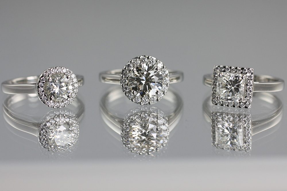 Three bespoke platinum halo engagement rings, round, cushion and princess cut