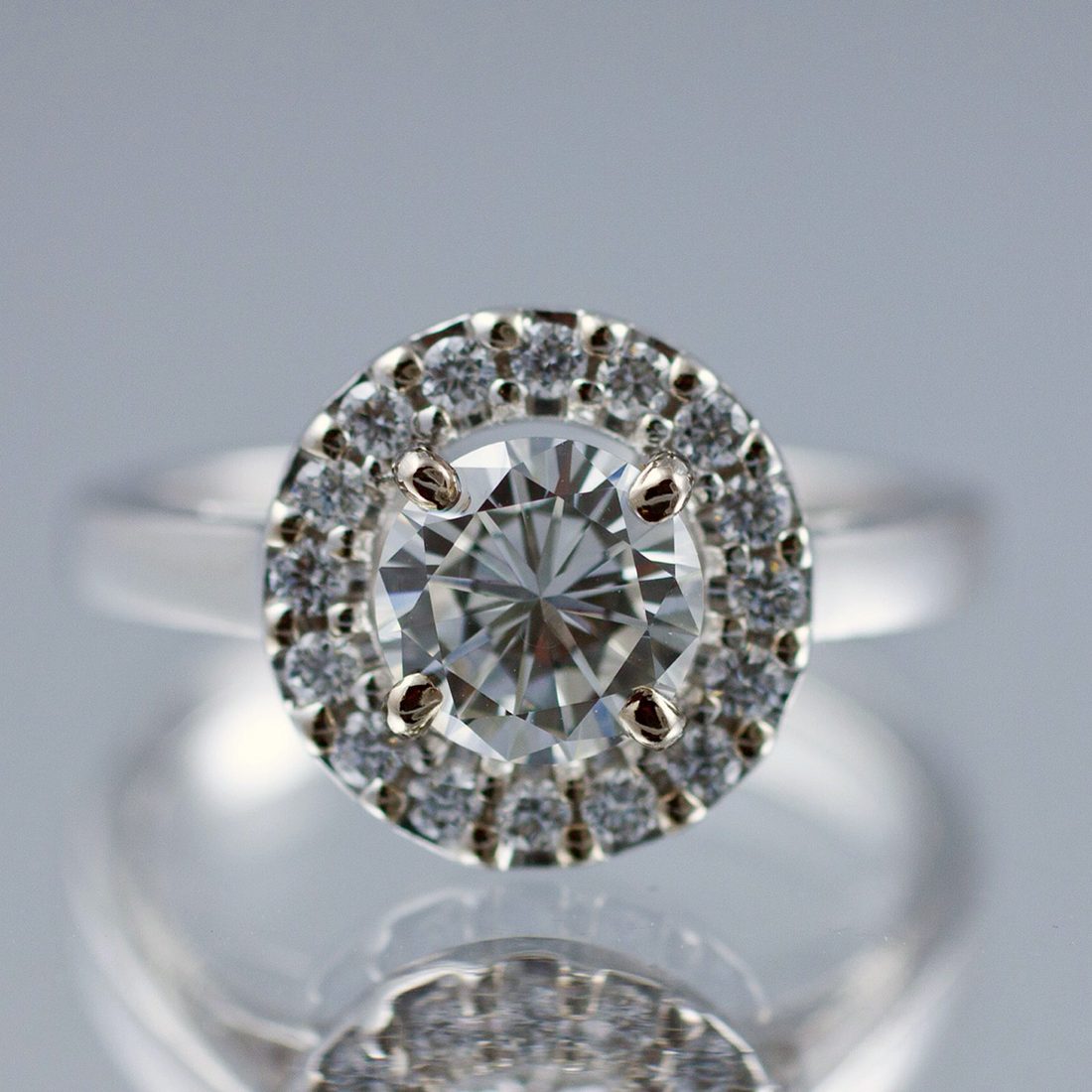 A round-brilliant diamond halo solitaire in platinum, set on the Nicholson Goldsmiths bench